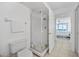Bright white bathroom with glass enclosed shower and tile floor with an ocean view from the bedroom at 4631 S Atlantic Ave # 8706, Ponce Inlet, FL 32127