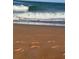 Sandy beach with footprints in the sand and waves crashing, showcasing a tranquil coastal setting at 48 Rosewood Ave, Ormond Beach, FL 32174