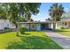 Charming home with a manicured lawn, mature trees, and a welcoming blue front door at 48 Rosewood Ave, Ormond Beach, FL 32174