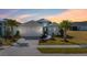 Well-maintained single Gathering home with palm trees, brick driveway, white exterior, and manicured lawn at sunset at 540 Good Life Way, Daytona Beach, FL 32124