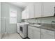 Bright laundry room features white cabinets, granite countertop, sink, and modern washer and dryer at 540 Good Life Way, Daytona Beach, FL 32124