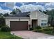 Charming single-story home featuring a brown two-car garage, brick driveway, and well-maintained landscaping at 5431 Hutchinson St, Port Orange, FL 32128