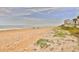 Expansive sandy beach with sparse vegetation and calm ocean view provides a serene coastal setting at 1155 Ocean Shore Blvd # 702, Ormond Beach, FL 32176