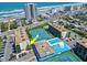 A vibrant aerial view of a beachside condo featuring a pool, tennis courts, and inviting lounge areas with stunning ocean views at 1441 N Atlantic Ave # 211, Daytona Beach, FL 32118