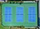 Aerial view of three tennis courts ready for play, surrounded by lush greenery and well-maintained grounds at 1441 N Atlantic Ave # 211, Daytona Beach, FL 32118