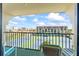 Sunny balcony view with chairs, road, buildings, tennis courts, and clouds overhead at 1441 N Atlantic Ave # 417, Daytona Beach, FL 32118