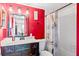 Stylish bathroom with a red accent wall, a marble vanity, and a bathtub with a decorative shower curtain at 1441 N Atlantic Ave # 417, Daytona Beach, FL 32118