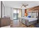 Bright bedroom with a balcony, wood accent wall, and light gray furnishings at 1441 N Atlantic Ave # 417, Daytona Beach, FL 32118