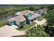 Aerial view of a teal blue house with a large driveway, lush landscaping, and a large pond in the background at 2189 Old Dixie Hwy, Ormond Beach, FL 32174