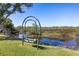 Backyard view of a swing, foot bridge, lush landscaping, and a pond in the background on a sunny day at 2189 Old Dixie Hwy, Ormond Beach, FL 32174