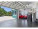 Garage with an epoxy floor, storage cabinets and a red car parked inside with the garage door partially open at 2189 Old Dixie Hwy, Ormond Beach, FL 32174