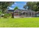 Large green lawn with a screened-in pool, blending outdoor living and relaxation at 27 Winding Creek Way, Ormond Beach, FL 32174