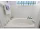 Bathroom featuring a large soaking tub, tiled floors, and glass block window at 27 Winding Creek Way, Ormond Beach, FL 32174