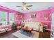 Bright pink bedroom features a ceiling fan, hardwood floors and lots of decor at 27 Winding Creek Way, Ormond Beach, FL 32174