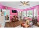 Bright pink bedroom featuring hardwood floors, window seats, and ceiling fan at 27 Winding Creek Way, Ormond Beach, FL 32174