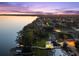 Aerial view showcases a stunning lakefront community with lush greenery and illuminated properties at dusk at 3130 Indian Trl, Eustis, FL 32726