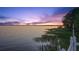 Beautiful waterfront view at sunset, featuring a dock and boat lift along the calm shoreline at 3130 Indian Trl, Eustis, FL 32726