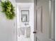Bright white half bathroom featuring a pedestal sink, modern mirror, and stylish decorative wreath at 330 Wall Ave, Ormond Beach, FL 32174