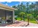 Serene backyard featuring a screened-in lanai, brick pavers, and a lush green lawn, perfect for outdoor living at 5635 Estero Loop, Port Orange, FL 32128