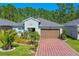 Charming single-story home with a well-manicured lawn, a brick driveway, and a two-car garage at 5635 Estero Loop, Port Orange, FL 32128
