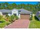 Inviting single-Gathering home with a brick paver driveway and a two-car garage, surrounded by lush greenery at 5635 Estero Loop, Port Orange, FL 32128