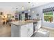 Kitchen island featuring granite countertops, stainless steel sink and faucet, white cabinets, and pendant lighting at 5635 Estero Loop, Port Orange, FL 32128