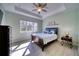 Bright bedroom featuring tray ceiling, a ceiling fan, wood-look flooring, and a window at 324 Coral Reef Way, Daytona Beach, FL 32124