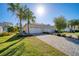 Charming single-Gathering home featuring a two-car garage, paver driveway, lush lawn, and swaying palm trees at 324 Coral Reef Way, Daytona Beach, FL 32124