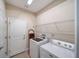 Well-organized laundry room with washer, dryer, storage shelves, and tiled flooring at 324 Coral Reef Way, Daytona Beach, FL 32124