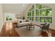 Staged living room featuring hardwood floors, a neutral sofa, and large windows with green views at 530 Estates Pl, Longwood, FL 32779