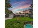 Charming single-story home featuring a well-manicured lawn, mature trees, and an inviting screened-in pool at 75 Knollwood Estates Dr, Ormond Beach, FL 32174