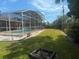 Wide backyard with a screened in pool area and lush lawn at 2612 Umbrella Tree Dr, Edgewater, FL 32141