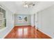 Bright bedroom featuring hardwood floors, a ceiling fan, and two windows providing natural light and neighborhood views at 394 Golf Blvd, Daytona Beach, FL 32118