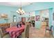 Open-concept dining room features light blue walls, chandelier, and travertine flooring, flowing into the living room and kitchen at 4008 Acoma Dr, Ormond Beach, FL 32174