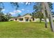 View of the well-kept backyard with a lush lawn, mature trees, and a screened-in patio at 518 Moon Rise Dr, Port Orange, FL 32127