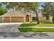 Inviting one-story home featuring a well-kept lawn, two-car garage, and mature shade trees in the front yard at 518 Moon Rise Dr, Port Orange, FL 32127