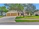 Inviting one-story home featuring a well-kept lawn, two-car garage, and mature shade trees in the front yard at 518 Moon Rise Dr, Port Orange, FL 32127