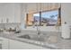 Close-up of a kitchen sink area featuring white cabinets, a granite countertop, and decorative accents at 133 Blue Heron Dr # C, Daytona Beach, FL 32119