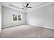 Spacious bedroom with tray ceiling, ceiling fan, large window, and plush carpeting at 1357 Liam Cir, Ormond Beach, FL 32174