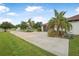 Long driveway leading to a two-car garage, complemented by mature landscaping and palm trees at 1357 Liam Cir, Ormond Beach, FL 32174