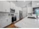 Bright kitchen featuring white cabinets, stainless steel appliances, marble countertops, and hardwood floors at 1357 Liam Cir, Ormond Beach, FL 32174