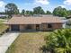 Aerial view of a brick home with a driveway and lots of green trees at 2 Wildwood Dr, Edgewater, FL 32132