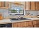 Classic kitchen featuring wood cabinets, a black sink, and window with lace valance offering a pleasant view at 2 Wildwood Dr, Edgewater, FL 32132