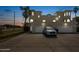 Beige two-story house with a two-car garage, palm trees, and wide driveway at dusk at 3074 Ocean Shore Blvd, Ormond Beach, FL 32176