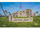 Fairwind Shores community sign with manicured lawn, tropical palm trees, and an American flag at 3370 Ocean Shore Blvd # 205-B, Ormond Beach, FL 32176