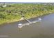 Stunning aerial view of a private pier with gazebo extending into the water, surrounded by lush greenery and ocean views at 44 Sandra Dr, Ormond Beach, FL 32176