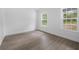 Empty bright bedroom showcasing modern wood-look floors, white trim, and two windows for a clean, inviting space at 5620 Ridgewood Ave, De Leon Springs, FL 32130
