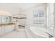 Well-lit bathroom featuring a soaking tub, a walk-in shower, double sinks, and plantation shutters at 6 Talaquah Blvd, Ormond Beach, FL 32174
