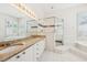 Bathroom with granite counters, double sinks, a walk-in shower and a large soaking tub at 6 Talaquah Blvd, Ormond Beach, FL 32174