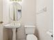 Charming powder room with pedestal sink, decorative mirror, and well-maintained toilet in a neutral color scheme at 6 Talaquah Blvd, Ormond Beach, FL 32174